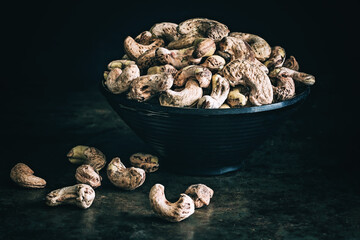 Raw unpeeled cashew nuts on a dark background