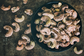 Raw unpeeled cashew nuts on a dark background