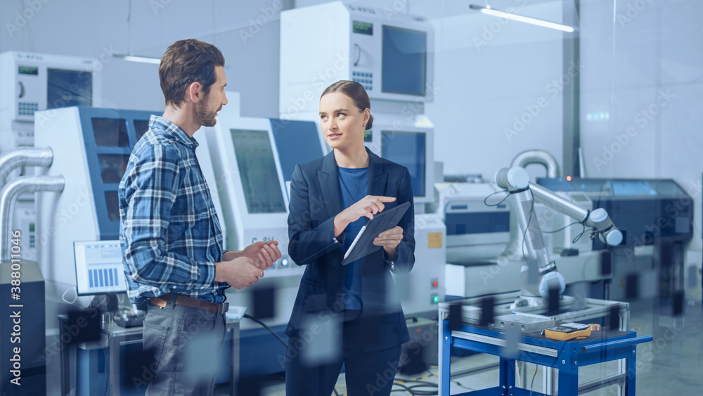 Poster Modern Factory: Female Project Manager and Male Engineer Standing, Talking, Using Digital Tablet for Programming and Monitoring Assembly Line. Industry 4.0 Facility with High-Tech CNC Machinery