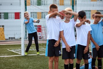children save goal with themselves, ready to accept penalty. in stadium. goalkeeper boy in the background