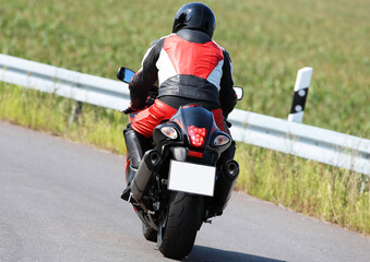 Motorradfahrer von hinten fährt davon