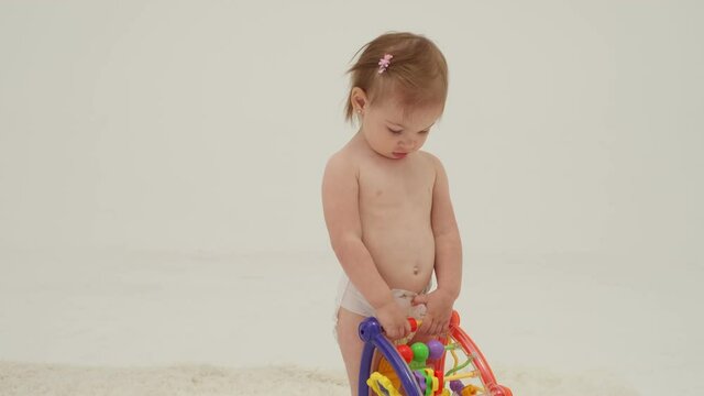 Happy little girl in diaper is playing toys. Slow motion