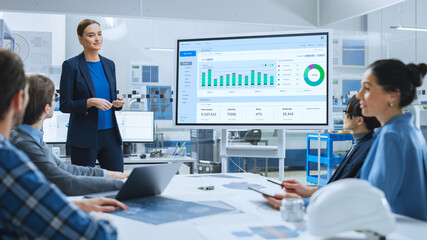 Modern Industrial Factory Meeting: Confident Female Engineer Uses Interactive Whiteboard, Makes...