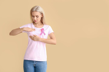 Young woman checking her breast on color background. Cancer awareness concept