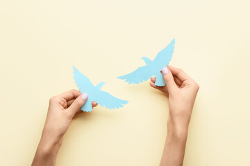 Female hands with paper doves on color background. International Day of Peace
