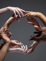 Saving kindness. Hands of different people in touch isolated on grey studio background. Concept of...
