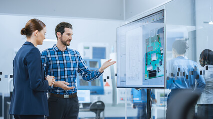 Female Computer Engineer and Male Project Manager Use Digital Interactive Whiteboard That Shows 3D...
