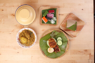 Nasi Lemak fragrant rice coconut milk with sambal friend peanut anchovy egg packed banana leaf round bamboo plate colorful nyonya kuih sweet desert palm leaf plate on wooden background