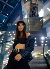 Woman poses on escalator in shopping mall.