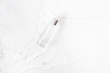 Glass Bottle with fluid collagen and hyaluronic acid, hydration skin. Top flatlay view copyspace. White Abstract water background