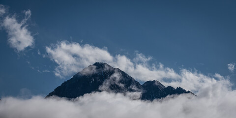 Fototapeta na wymiar peak of mount Thaneller in reutte austria with clouds at the bottom and blue sky