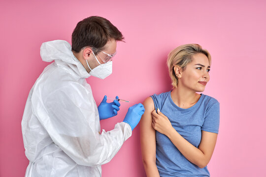 confident doctor with syringe doing injection vaccine,flu,influenza in the shoulder of young caucasian woman, healthcare concept