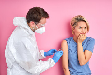 confident doctor with syringe doing injection vaccine,flu,influenza in the shoulder of young caucasian woman, healthcare concept