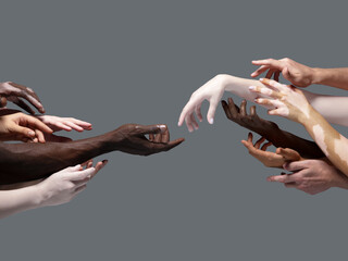 Creation of Adam. Hands of different people in touch isolated on grey studio background. Concept of...