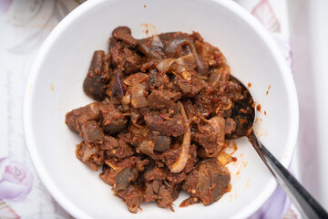 A picture of a locally prepared dish made up of spicy peppered goat known as Asun