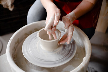 Female hands crafting a pottery cup on a potter's wheel. Handmade and crafting concept. Top horizontal view copyspace.