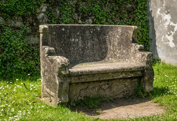 Antique stone bench in an old green summer garden
