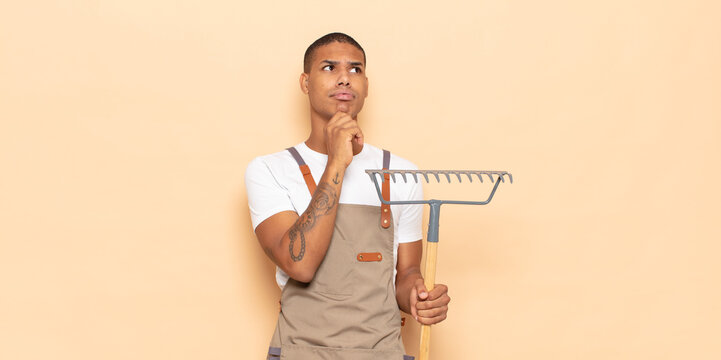 young black man thinking, feeling doubtful and confused, with different options, wondering which decision to make