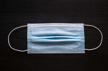 Medical blue white mask on black wooden background