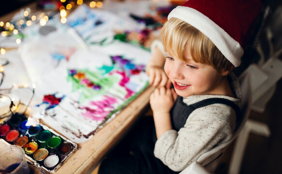 Top view of small boy indoors at home at Christmas, painting pictures.