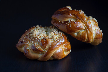 Two sweet buns on the black wooden table with dark background