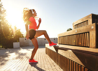 Sporty woman doing dynamic exercise near steps.
