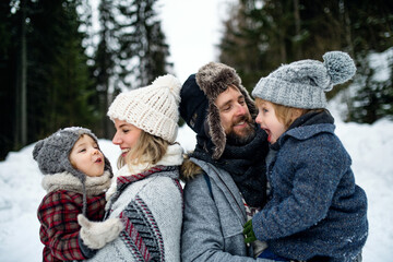 Fototapeta premium Father and mother with two small children in winter nature, standing in the snow.