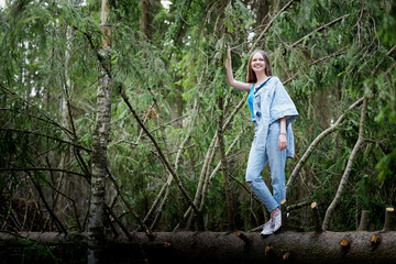 Beautiful young brunette woman with long hair in a forest pines and firs on a summer day