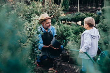 senior man with his grandchild working in his plant nursery