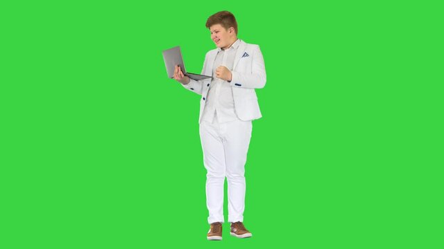 Boy Standing Using Laptop And Making Win Gesture on a Green Screen, Chroma Key.