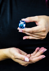 Elegant woman's hands hold a large deep blue topaz stone