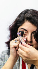 Gemologist woman observes a precious stone with her magnifying glass while holding it with her jewelry tweezers