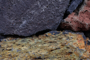Yellow, orange and grey rocks together close view, part of a wall texture