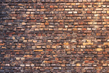 The old wall of the building is made of multi-colored bricks, darkened by time, smoked with soot.