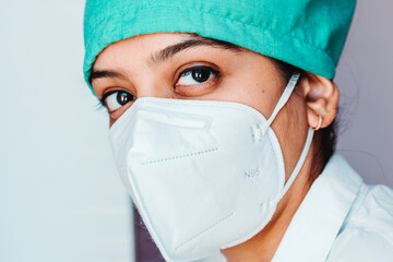 Close up portrait of young Indian female surgeon doctor in Emergency room wearing mask and cap during corona virus pandemic
