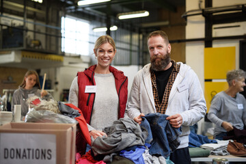 Volunteers sorting out donated clothes in community charity donation center.