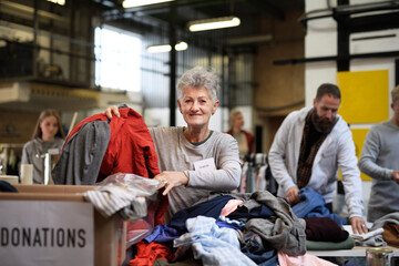 Volunteers sorting out donated clothes in community charity donation center.