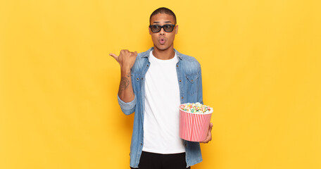 young black man looking astonished in disbelief, pointing at object on the side and saying wow,...