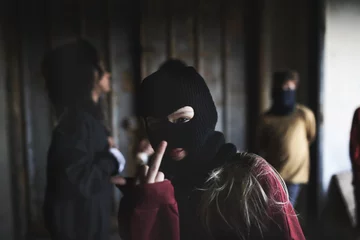 Foto op Canvas Girl with mask from teenagers gang standing indoors in abandoned building, showing middle finger. © Halfpoint