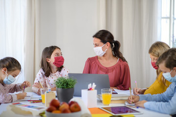 Group of homeschooling children with teacher studying indoors, coronavirus concept.