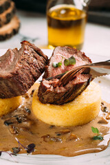 Eating beef medallion on corn porridge with sauce
