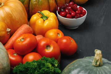 Assortment of vegetables including pumpkin, tomatoes and peppers on black background