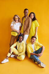 students from different countries in studio with yellow background, mixed race people in one group, friendly stylish people posing, look at camera