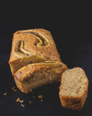 Slices of banana nut bread loaf placed on the dark background. Homemade delicious pastries. Close-up view.