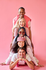 Fototapeta na wymiar smiling mixed race group of people in studio on pink background, attractive ladies and handsome guys in cool stylish wear outfit