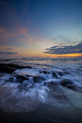 Amazing seascape. Beach with rocks and stones. Low tide. Motion water. Slow shutter speed. Soft focus. Mengening beach, Bali, Indonesia. Vertical layout.