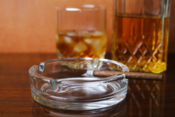 Lighted cigar in a glass round ashtray close-up, selective focus, bokeh.