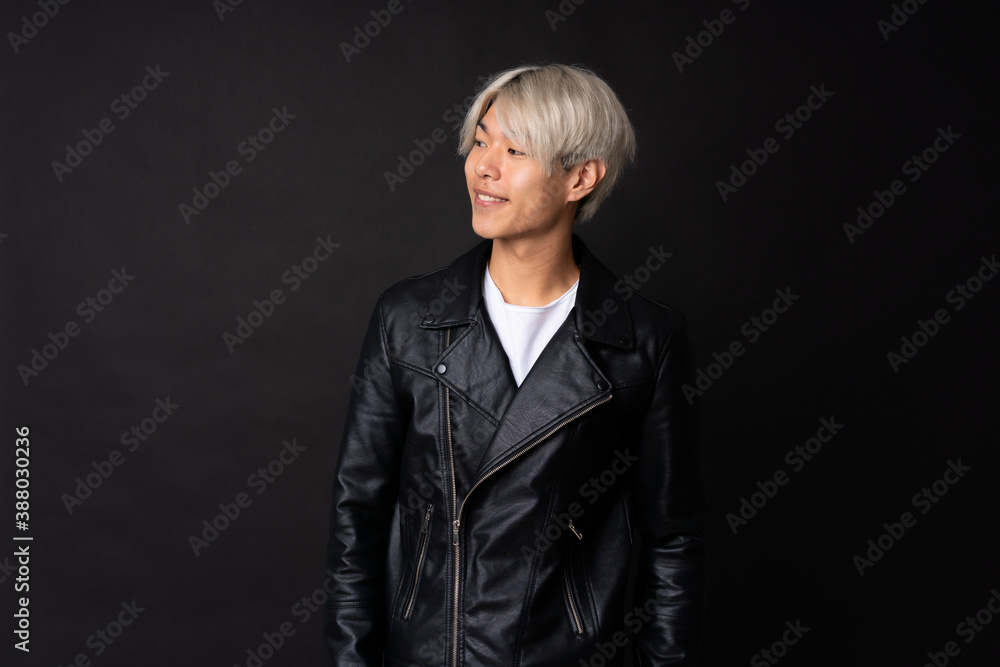 Wall mural Young asian man over isolated black background looking side