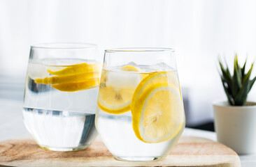 Close up two glasses of homemade detox drink, lemon and a glass of warm room temperature water. Detox drinks woman healthy lifestyle losing weight
