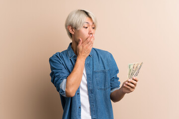 Young asian man over isolated background taking a lot of money